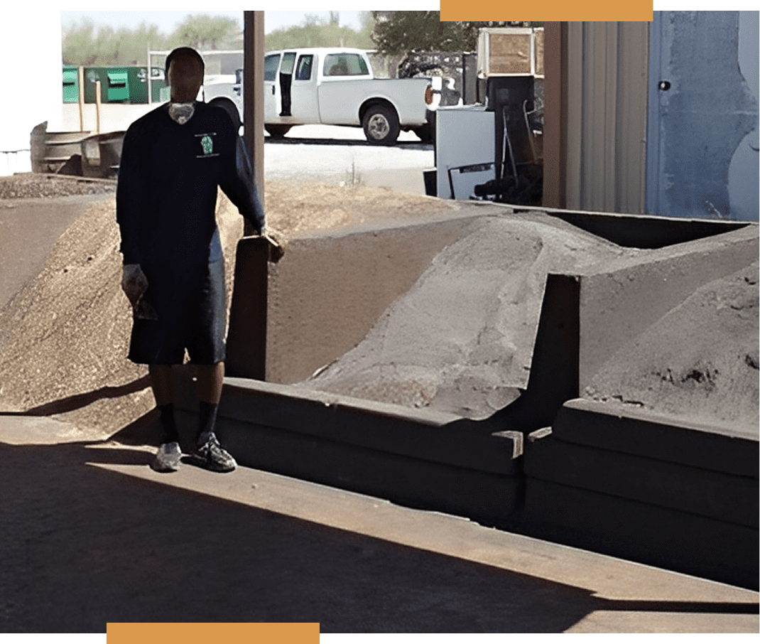 Man standing by large piles of sand.