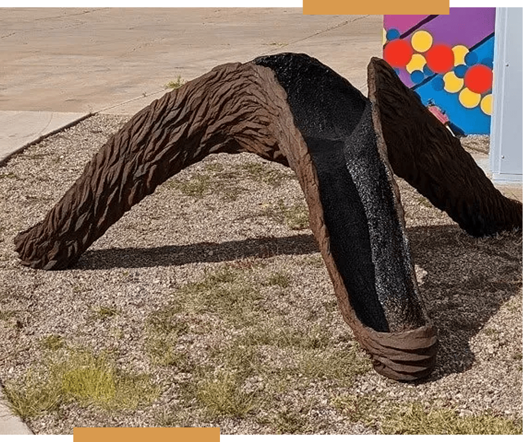 Abstract outdoor sculpture on rocky ground.