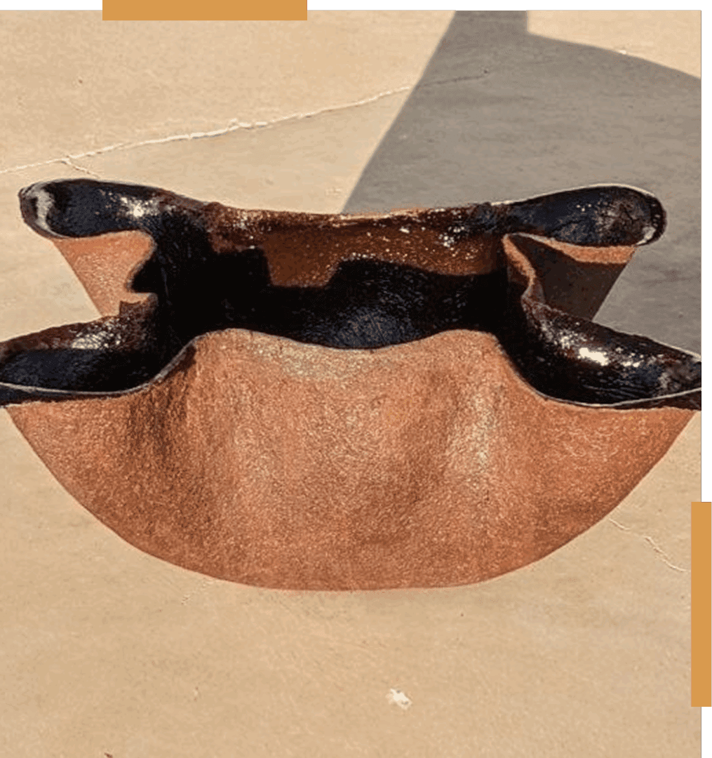 Brown, abstract ceramic sculpture on concrete surface.